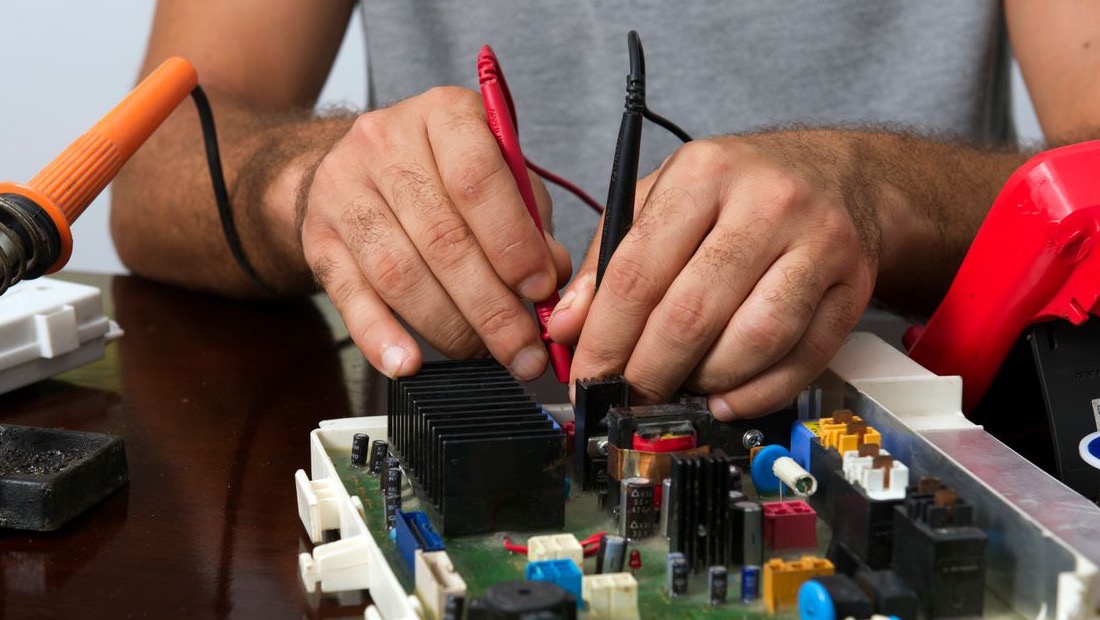 Hands testing a real circuit board with meter probes